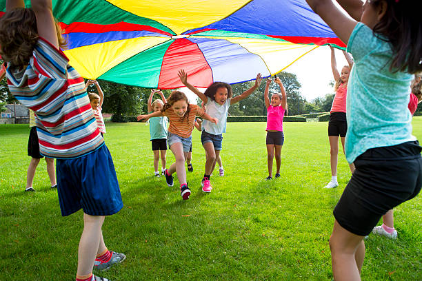 Children playing a game with a colourful Parachute
